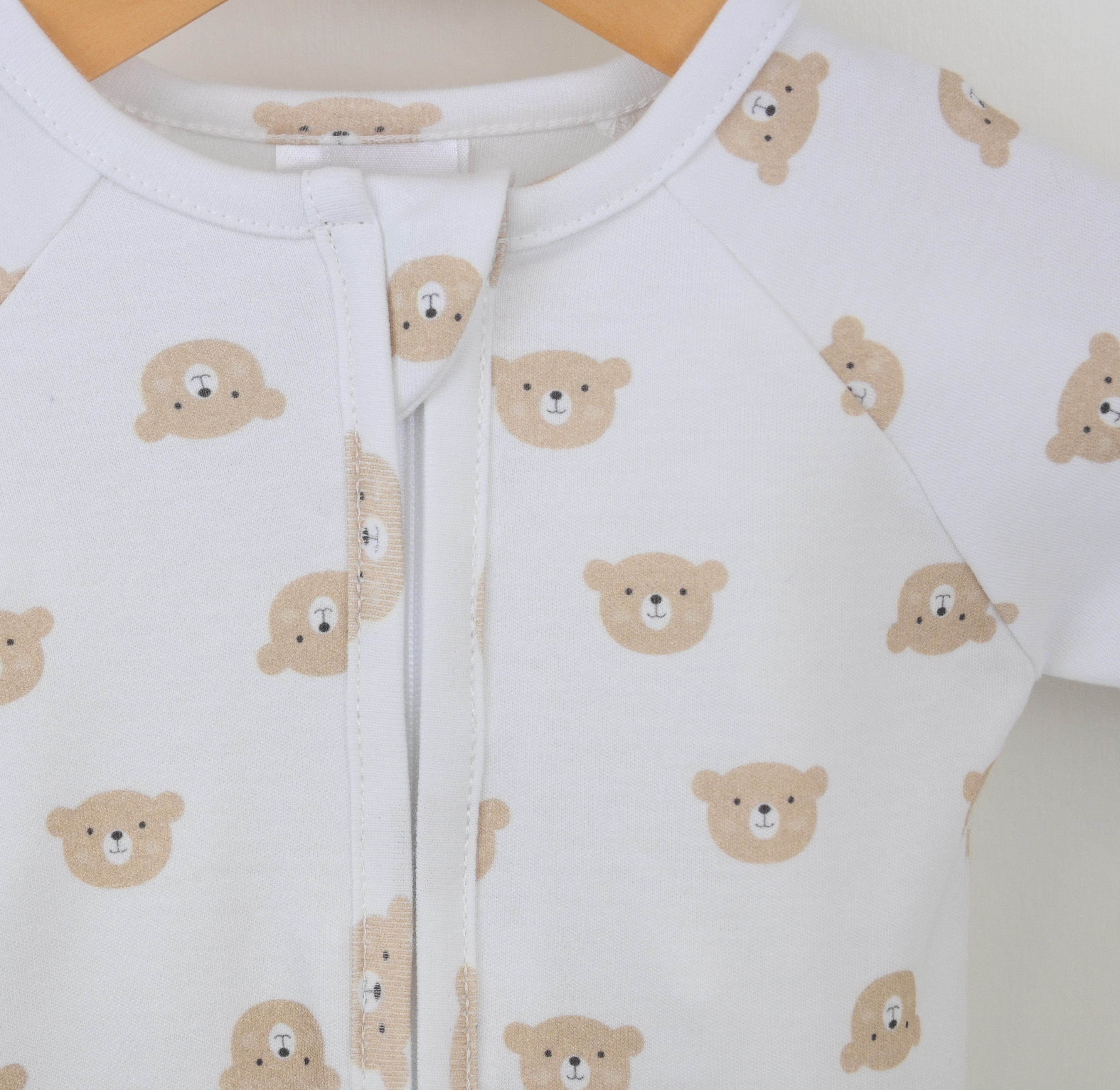White baby onesie with bear pattern on a hanger