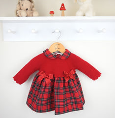 Red dress with plaid pattern on a hanger against a white background