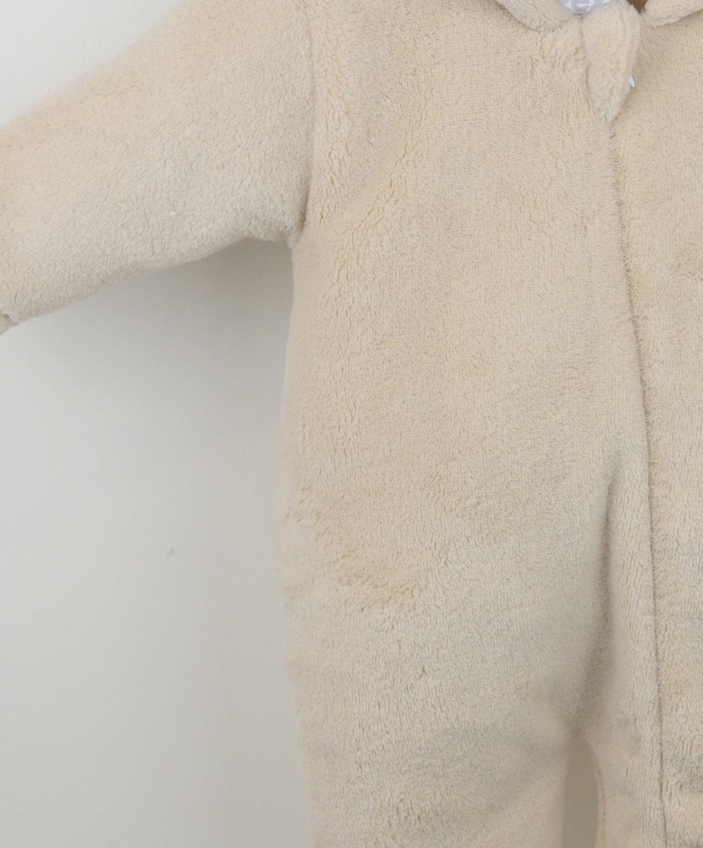 Beige fleece baby onesie on a white background