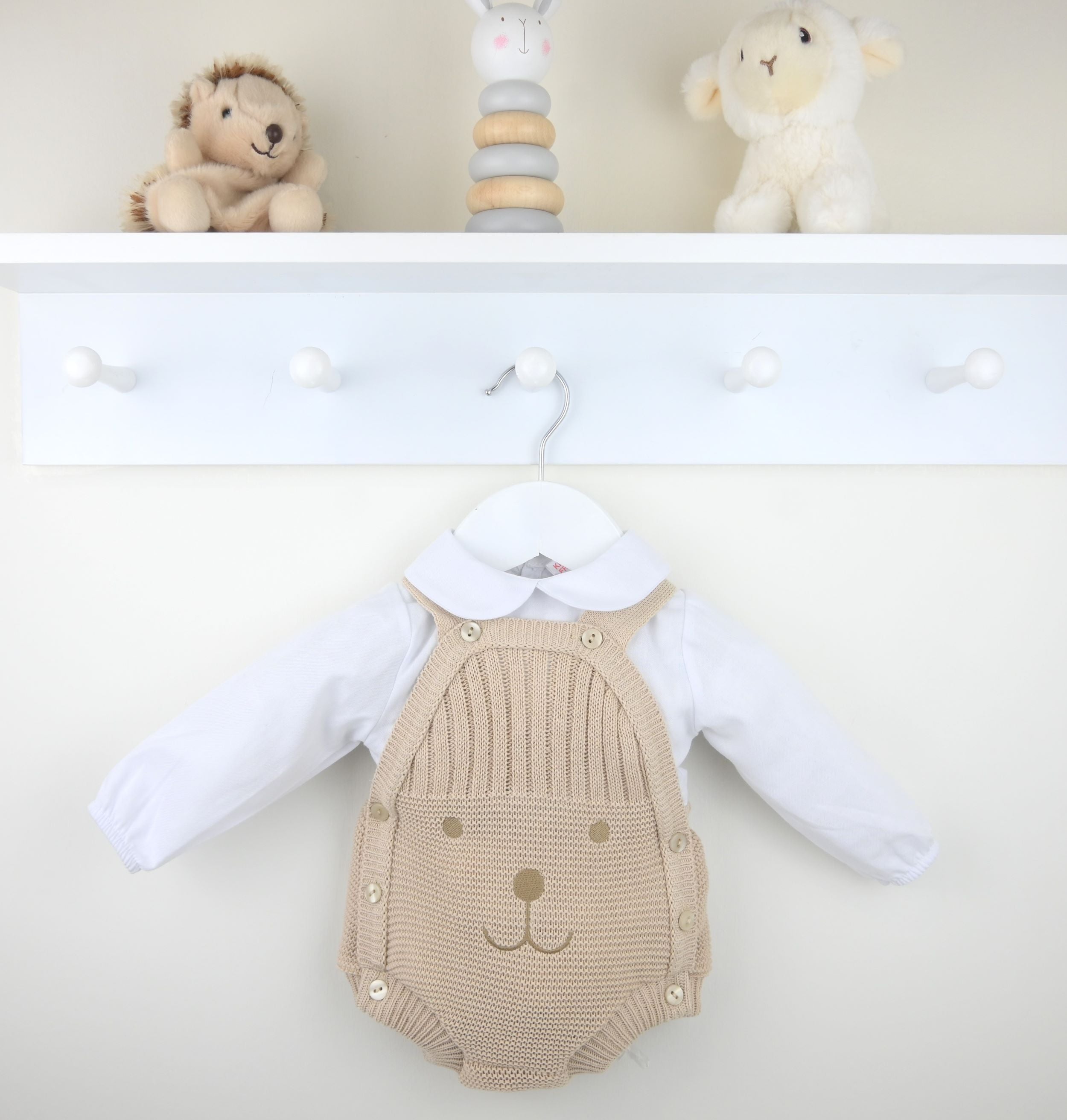 Baby romper with bear design on a white surface, surrounded by toys.